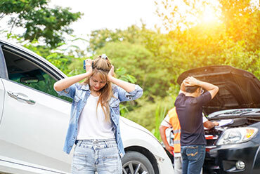 Frustrated individuals standing next to damaged vehicles after a car accident - The Law Offices of Luke T. Moreau, ESQ.